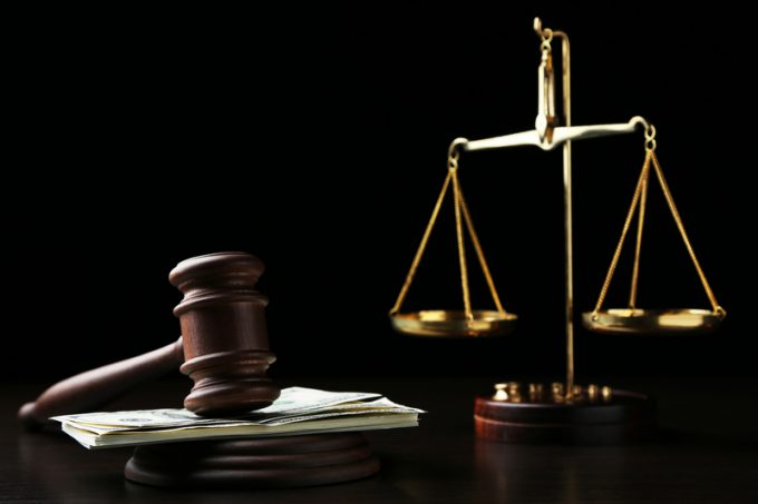 Judge gavel with dollars and scales on wooden table